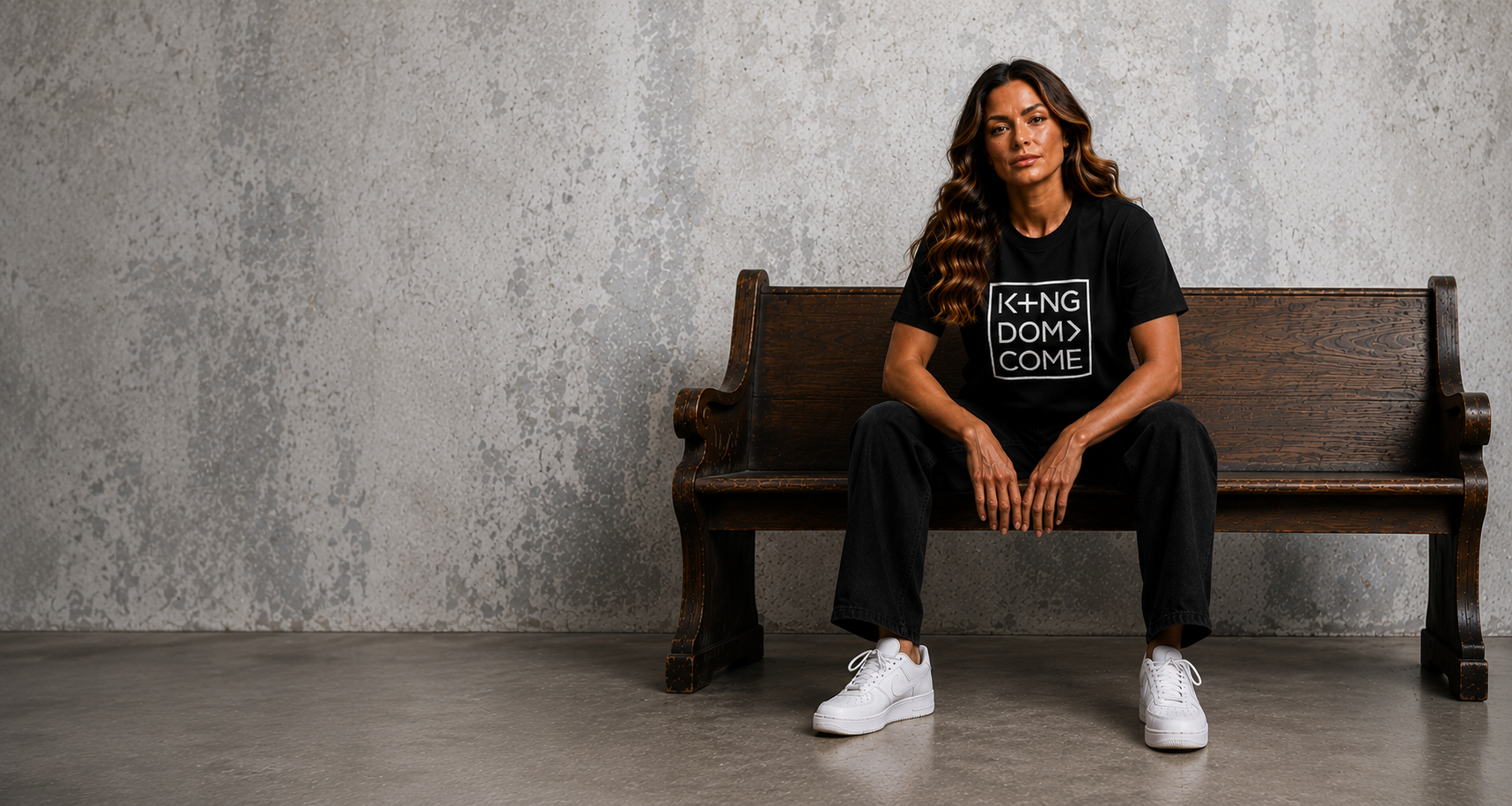 Woman seated on a church pew wearing the Kingdom Come tee
